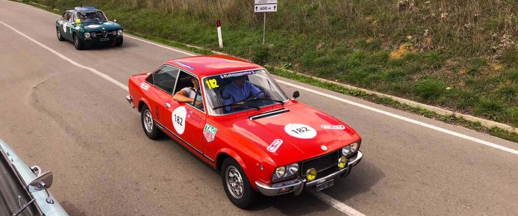 Roter Fiat 124 Sport Coupé bei der Targa Florio Classica auf einer Landstraße im sizilianischen Hinterland.
