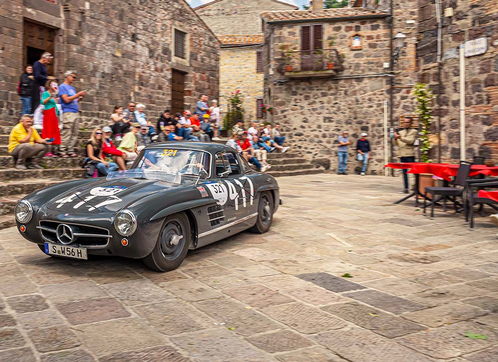 Mercedes-Benz 300 SL Coupé driving through a historic Italian village during the Mille Miglia.